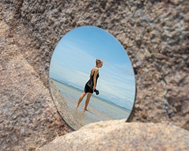 Photo woman at the beach in summer posing with round mirror