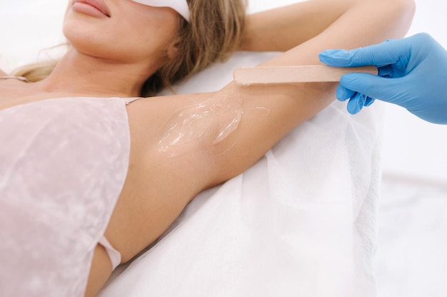 Woman beautician in blue glowes applies contact gel on the armpit of a woman for laser hair removal