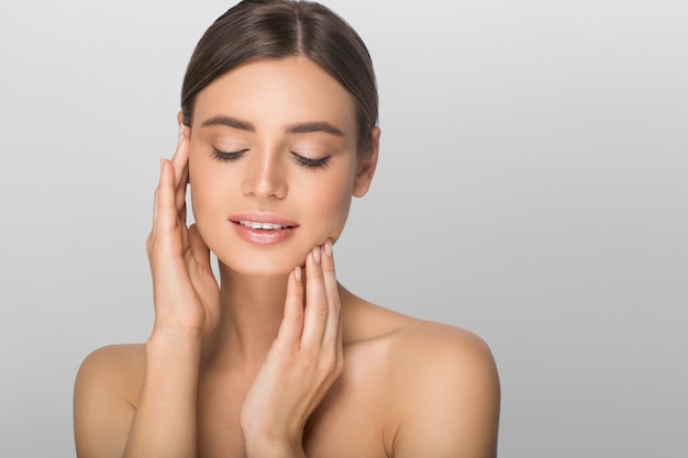 Woman beauty portrait touching her face. Color background. Gray