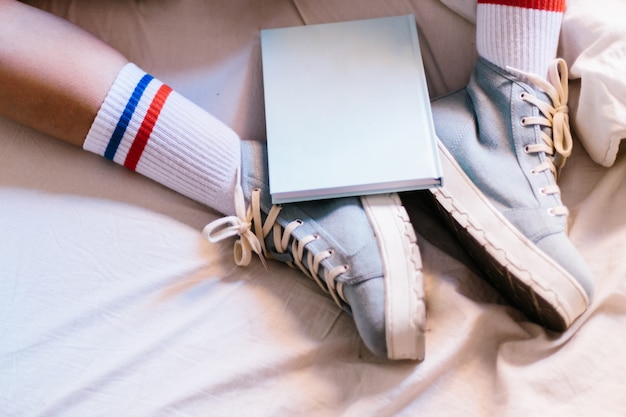 Woman in bed with blue slippers  at home starting to read a book