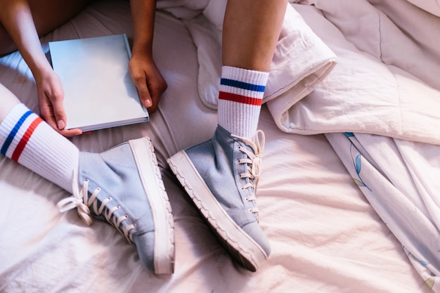 Woman in bed with blue slippers at home starting to read a book