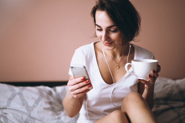 Woman in bed with coffee and phone