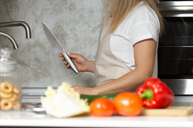 Woman in a beige apron prepared a knife for slicing vegetables