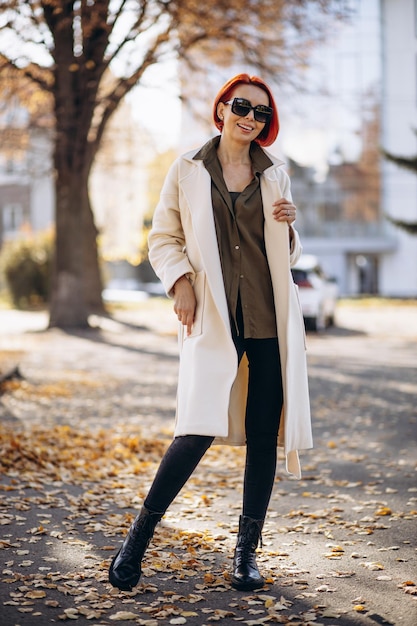 Woman in beige coat standing in autumn park