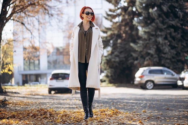 Woman in beige coat standing in autumn park