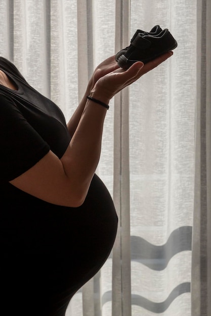 Woman belly holding baby booties