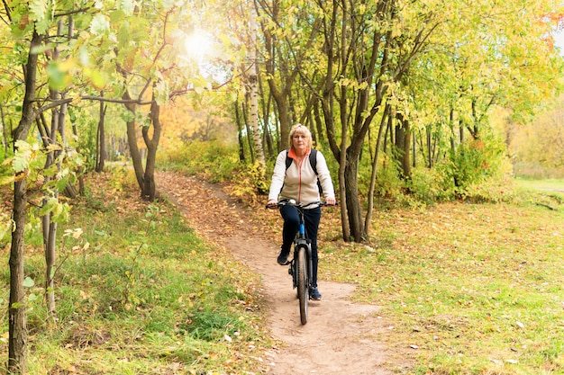 A woman on a bicycle rides on the road in the city park