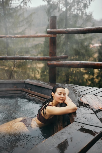 Woman in bikini bathing in japanese style bath outdoors