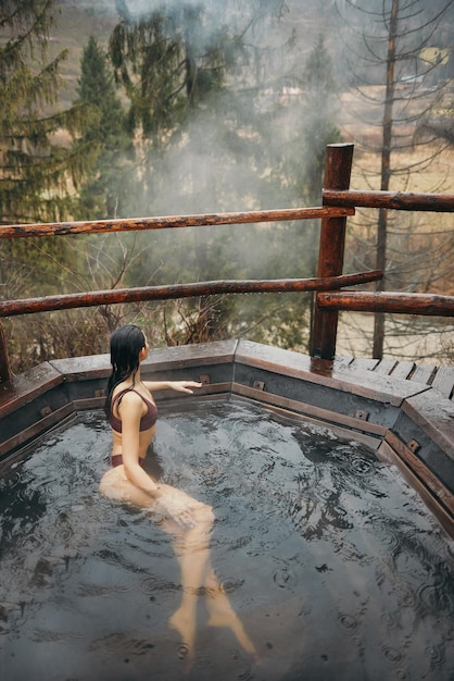 Woman in bikini bathing in japanese style bath outdoors