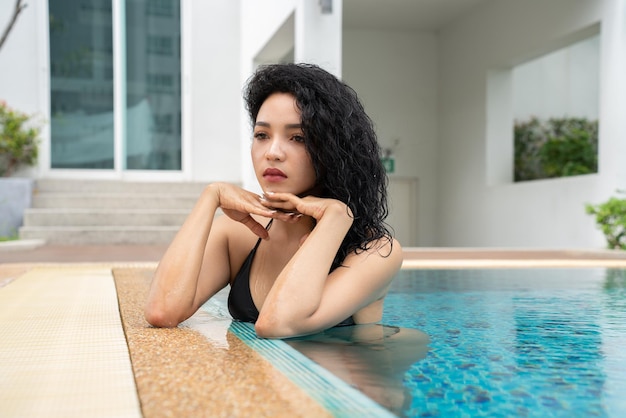 Woman in the bikini at pool Swimming pool tanned slim and shapely body Girl enjoying travel holidays at resort luxury overwater bungalow