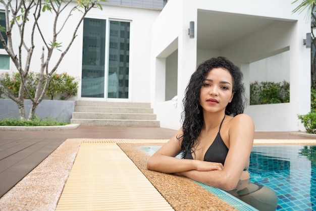 Woman in the bikini at pool Swimming pool tanned slim and shapely body Girl enjoying travel holidays at resort luxury overwater bungalow