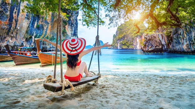 Woman in bikini relaxing on swing at Ko lao lading island Krabi Thailand