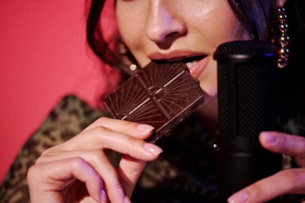 Photo woman biting dark chocolate bar