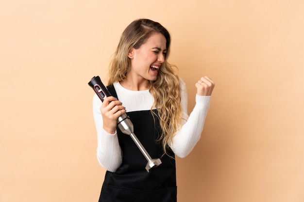 Woman in a black apron with a hand blender