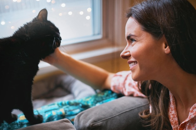 Woman black cat and petting with smile in home scratch and support animal or companion for love Female person relax and peace in living room to stroke pet bonding and connection for loyalty