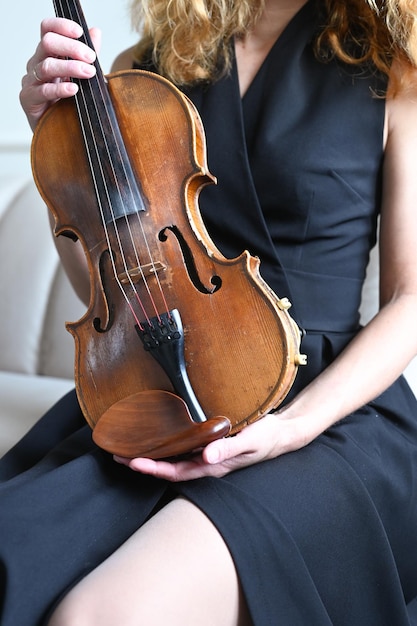 Woman in black dress holding violin in her hands cropped view Vertical photo