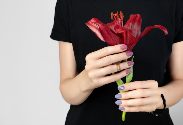 Woman in a black dress holds a burgundy lily