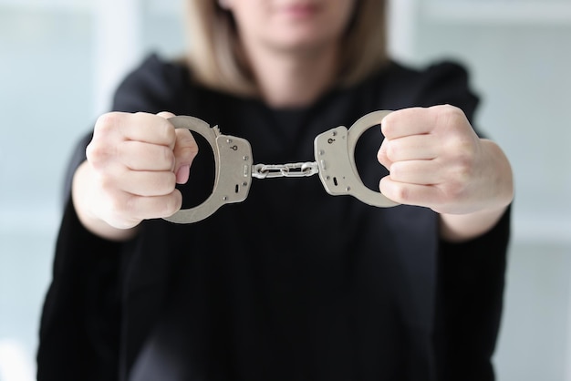 A woman in a black dress holds handcuffs a closeup judge in a black mantle accusative sentence