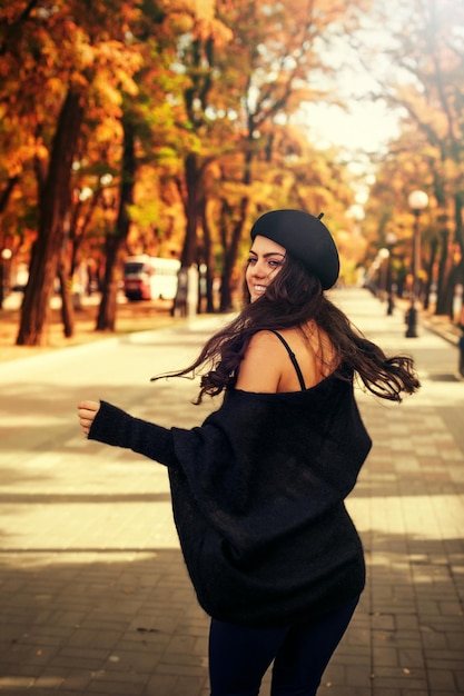 Woman in black hat on the background of autumn leaves