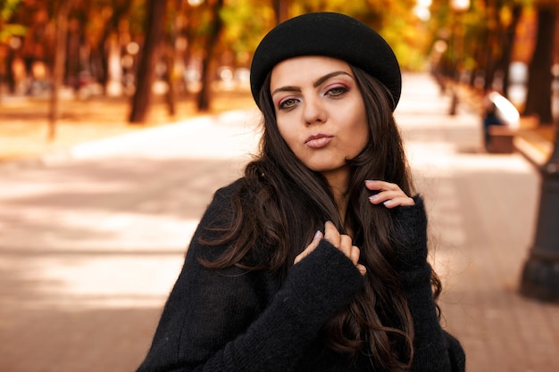 Woman in black hat on the background of autumn leaves