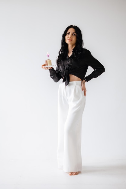 A woman in a black shirt and white pants holds a bottle of juice.