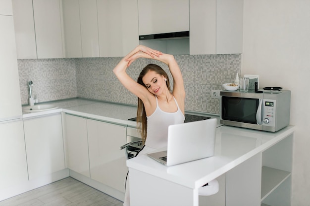 Woman in black suit smiling at the laptop in kitchen