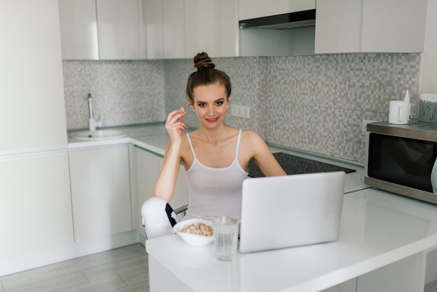 Woman in black suit smiling at the laptop in kitchen