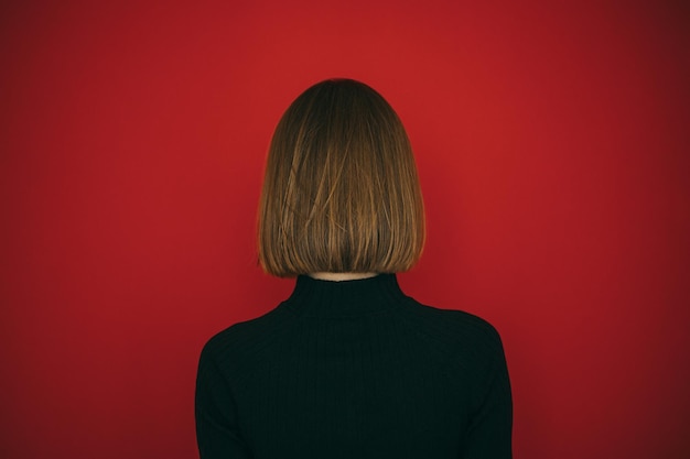 Woman in black sweater and with hairstyle bob isolated on red background