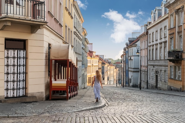 woman blonde in dress goes down the street in the old city