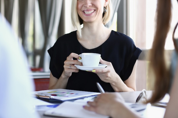 Woman blonde talking to friends in a cafe for a cup of coffee