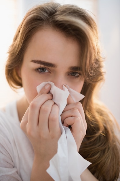 Woman blowing her nose on couch in the living room