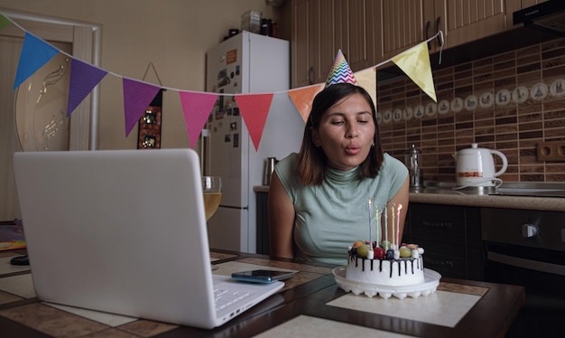 Woman blowing out the candle on the birthday cake and making video call