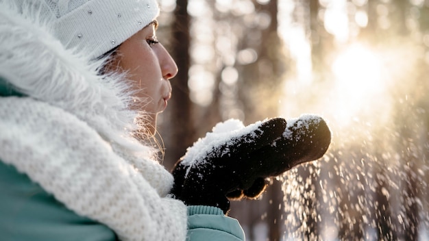 Woman blowing snow outdoors in winter