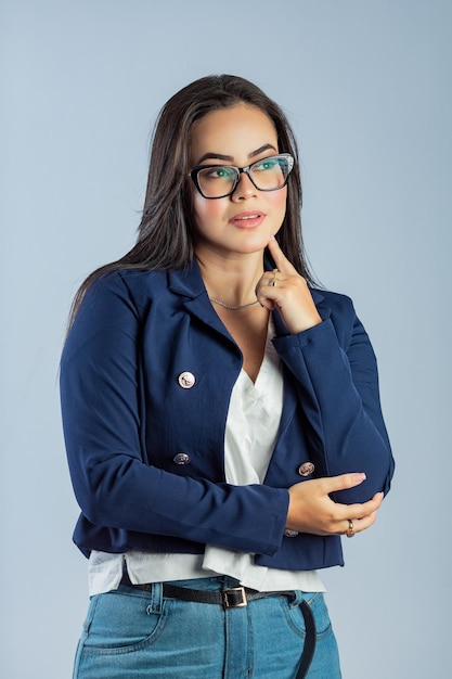 A woman in a blue blazer stands in front of a blue background.