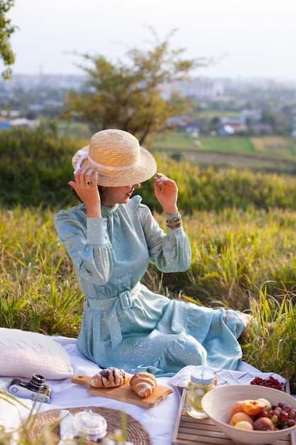 A woman in blue dress sits on a picnic in a park with panoramic view