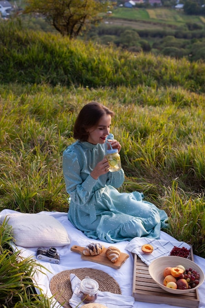 A woman in blue dress sits on a picnic in a park with panoramic view