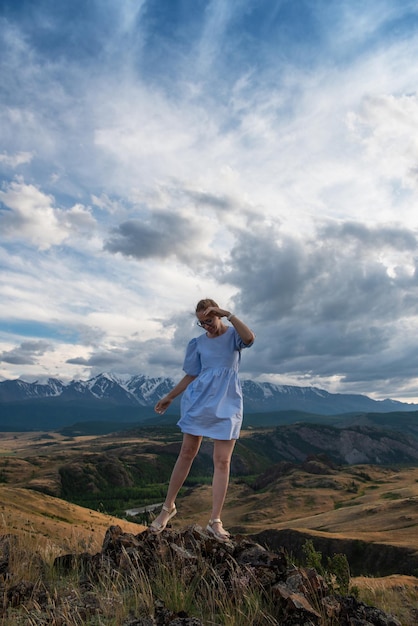 Woman in blue dress in summer altai mountains in kurai steppe