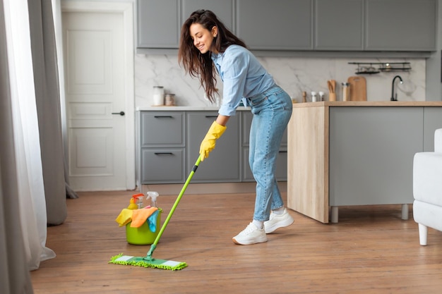 Woman in blue shirt cleaning floor with mop and bucket