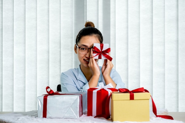 Woman in a blue shirt holding a white gift box tied with a red ribbon present