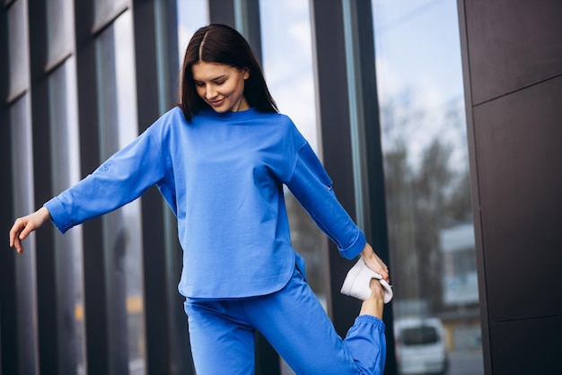 Photo woman in blue sports wear stretching outside the street