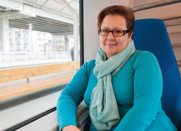 Woman in a blue sweater and scarf with glasses travels in a train Model plus size