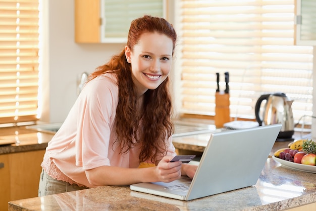 Woman booking flight online in the kitchen