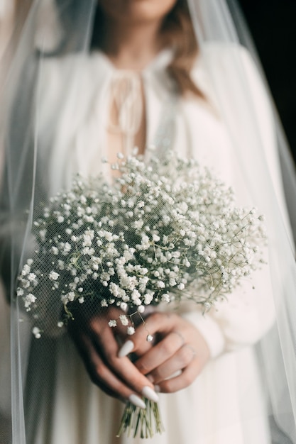 Woman bride in wedding dress holding white bouquet in hand