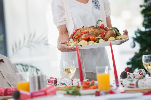 Woman bringing roast chicken at table