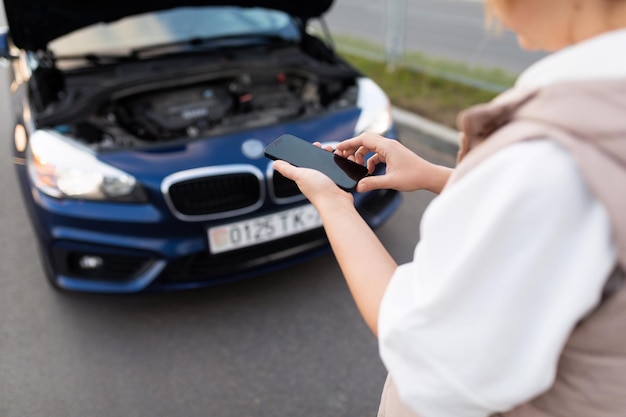 A woman next to a broken car calls a technical support service using a phone sharpness on a mobile