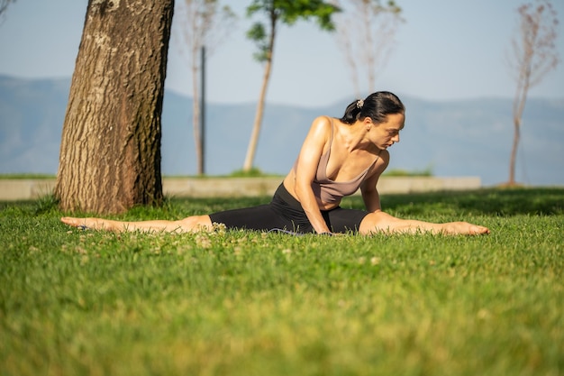 A woman in brown sport bra and black short sitting on yoga mat doing maditation with hand together a