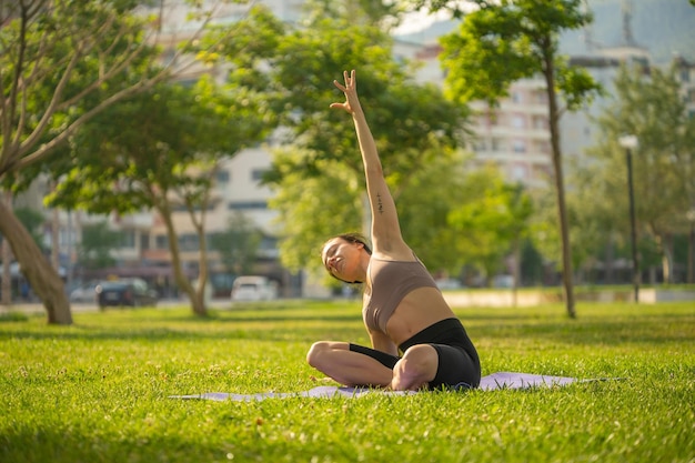 A woman in brown sport bra and black short sitting on yoga mat doing maditation with hand together a