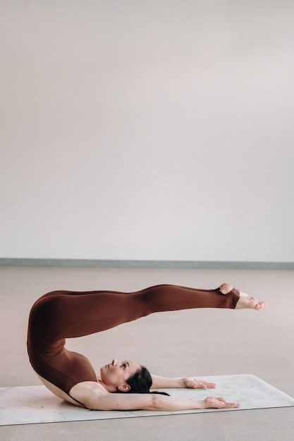 A woman in a brown suit does yoga in a fitness room Healthy lifestyle fitness training selfcare