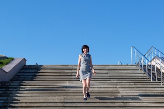 Woman brunette in striped dress descends a wide staircase