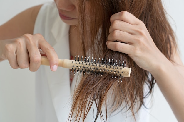 Photo woman brushing her wet messy hair after bath with comb, thin hair porblem. hair damage, health and beauty concept.